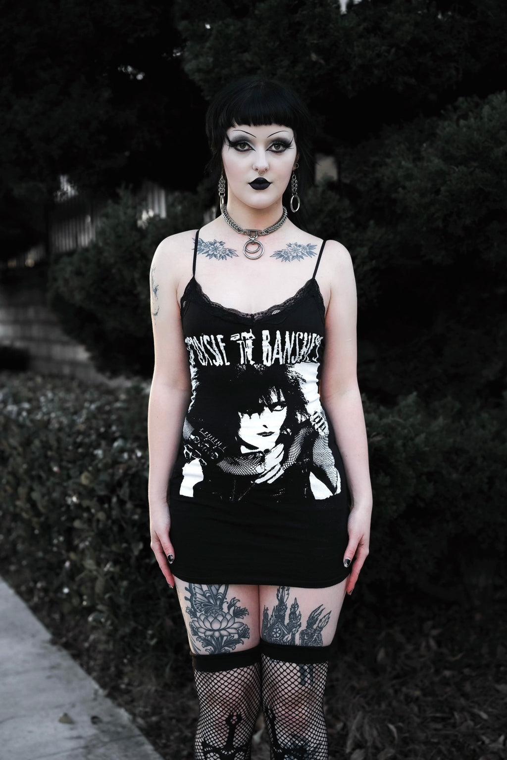 Person wearing a black tank top with graphic design and text, standing outdoors.