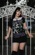 Person wearing a graphic t-shirt with a design and text, standing in front of an ornate metal gate.