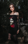 Woman wearing a black dress with a graphic design in a dark, outdoor setting