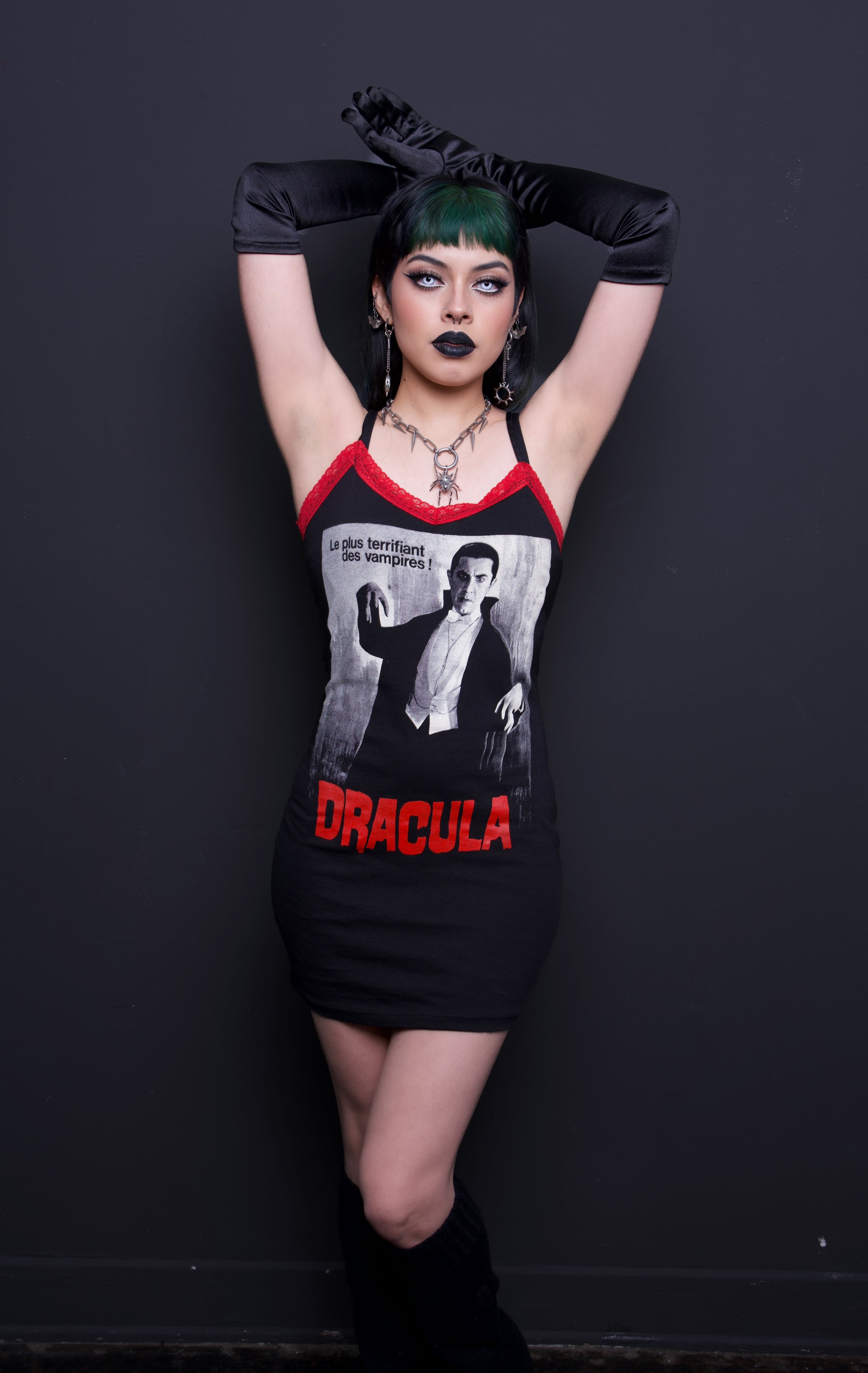 Person wearing a black dress with red lace and with 'Dracula' print against a dark background