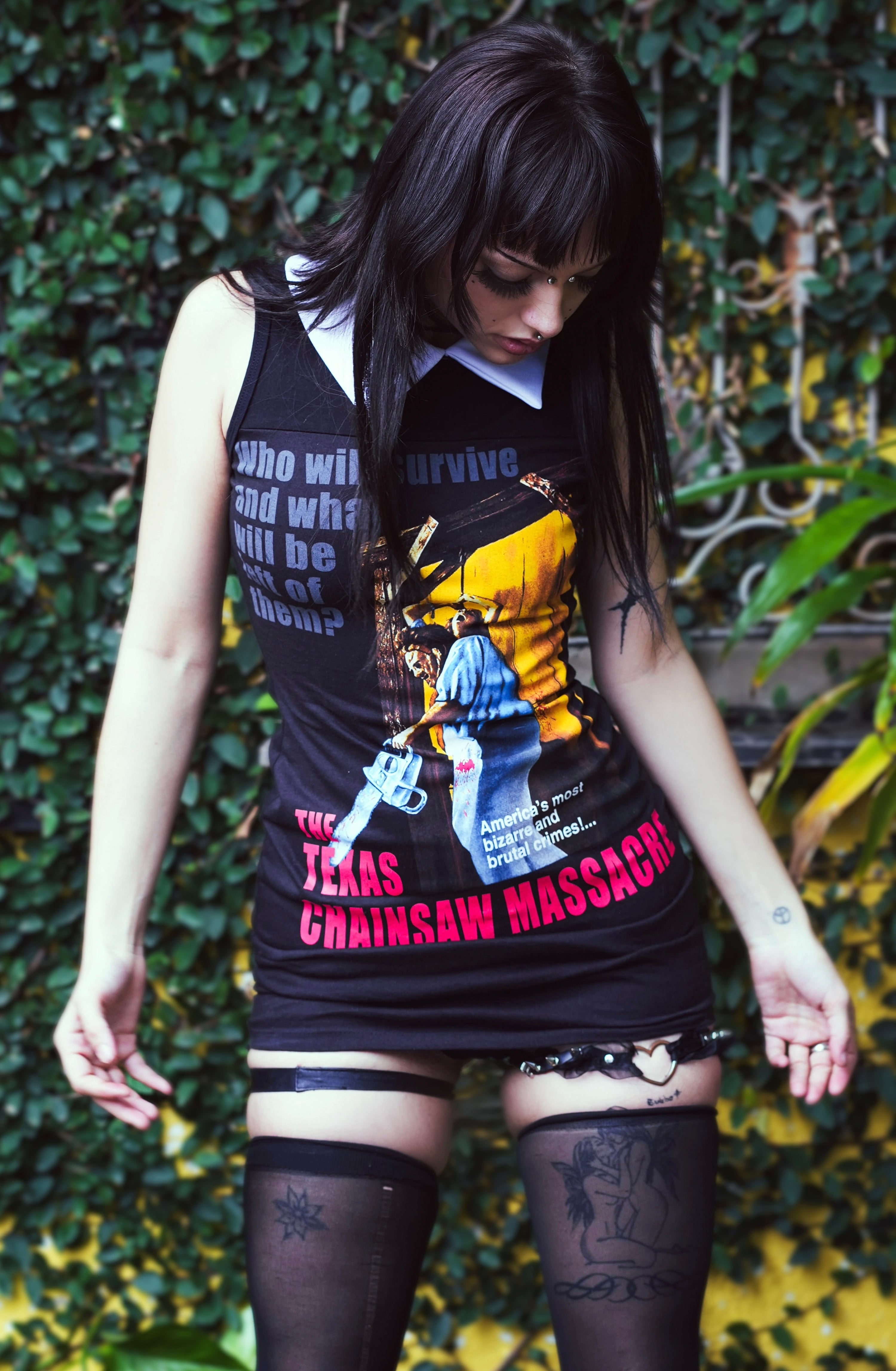 Person wearing a tank top with graphic design against a green leafy background